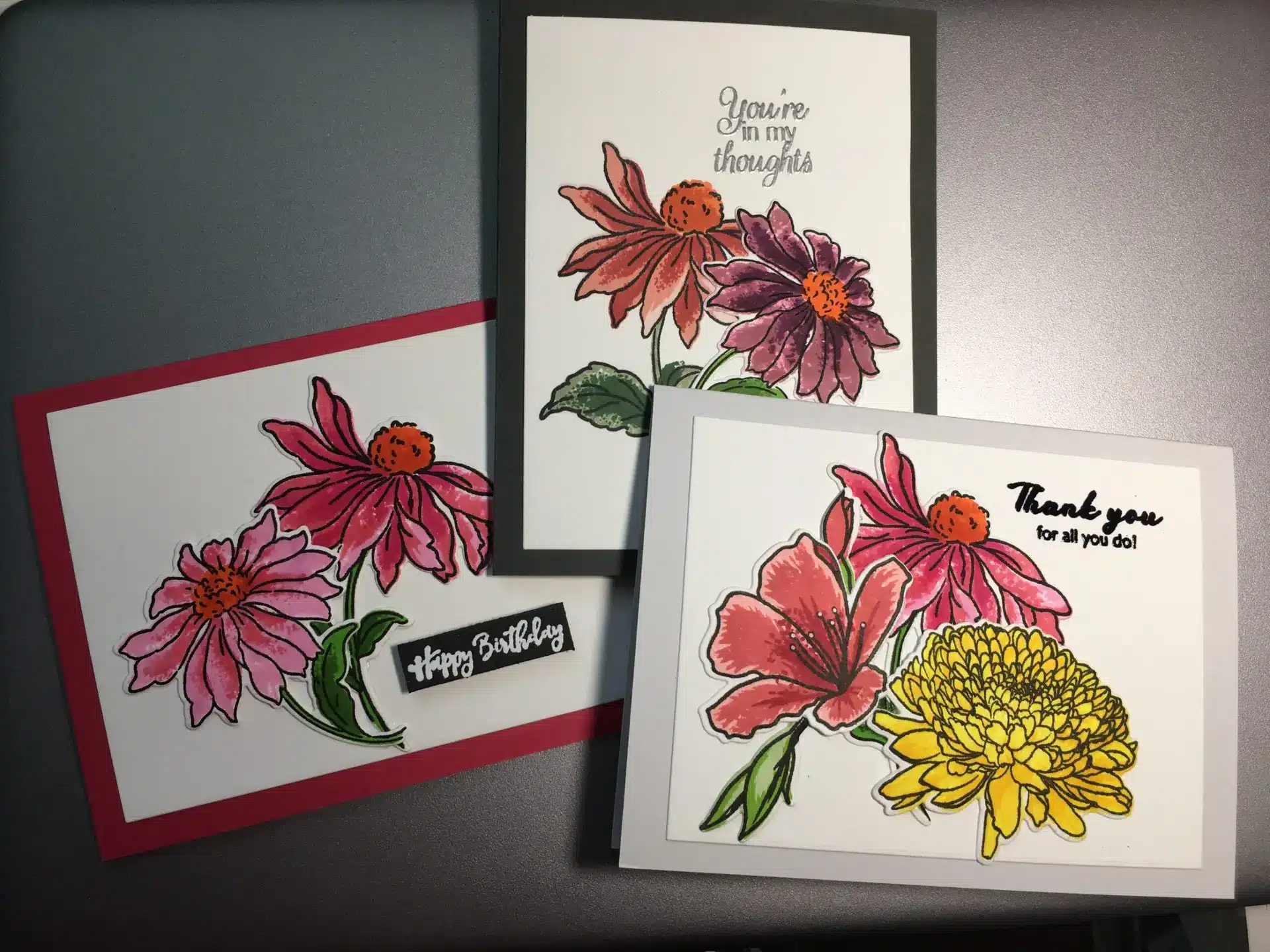 Three handmade greeting cards with colorful coneflowers on them.