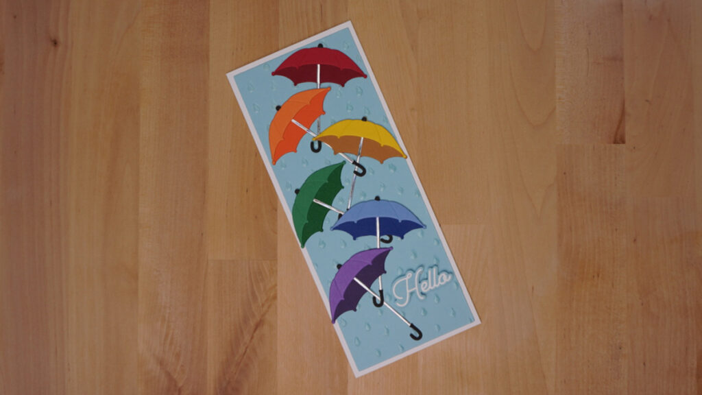 The fourth card made with products from Spellbinders' January features six umbrellas in rainbow colors with a simple sentiment saying hello.
