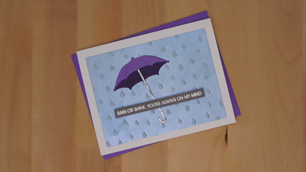 The first of 4 cards made with products from Spellbinders' January release.  This one features a single purple umbrella over a rainy blue sky.