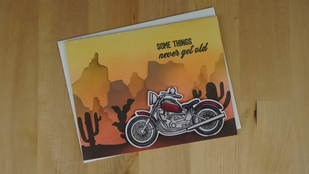 This is a photo of a motorcycle on a anniversary card.  And it's perched in front of a beautiful dessert sunset.  