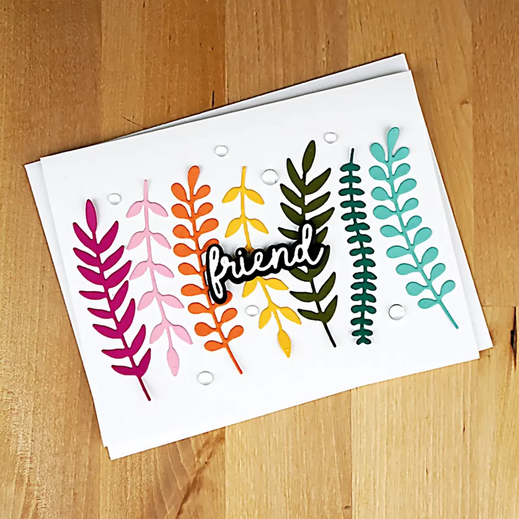 Gorgeous card that has die-cut sprigs in rainbow colors arranged vertically across the front of a white horizontal A2 card base.