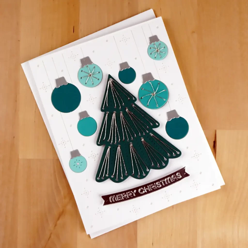 Card created using Spellbinders October 2023 Stitching Die of the Month.  This one has a white background with a teal Christmas tree and ornaments.