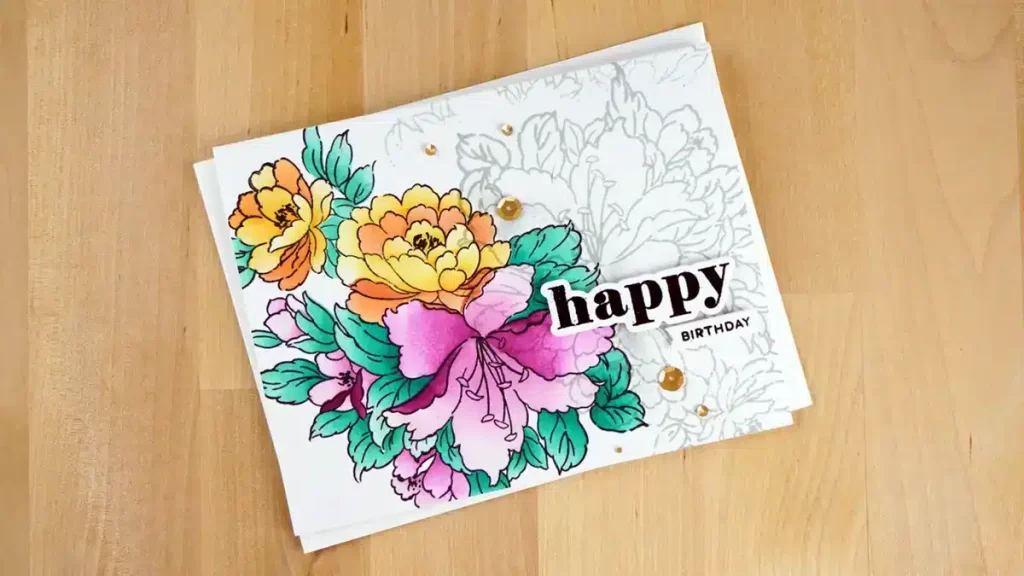 A birthday card featuring colorful hand-drawn flowers created with Altenew Fresh Dye Inks and the word "happy" in bold black letters, with "birthday" written in smaller text below it, set against a wooden background. Perfect for card making enthusiasts.