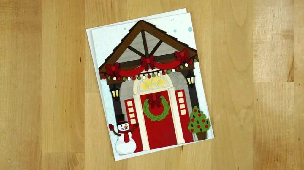 A festive Christmas card featuring a charming house and adorable snowman, celebrating the joy of the season as we countdown to Christmas.