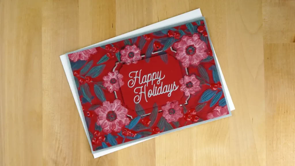 A red and blue card with notched corner florals and the words happy holidays on it.