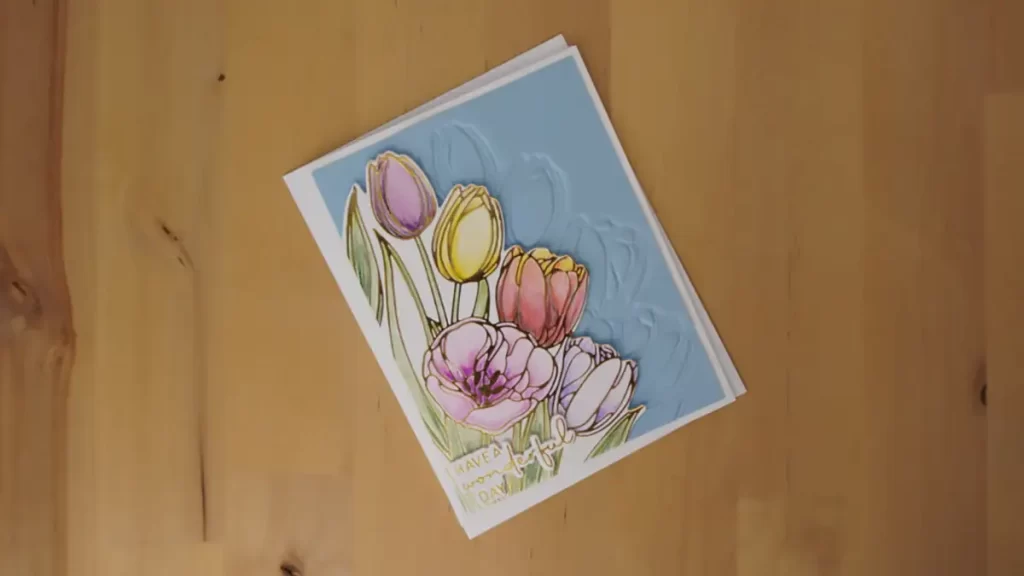 A card with tulips on it is sitting on a wooden table.