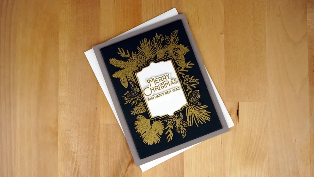 A christmas card with gold foil on a wooden surface.