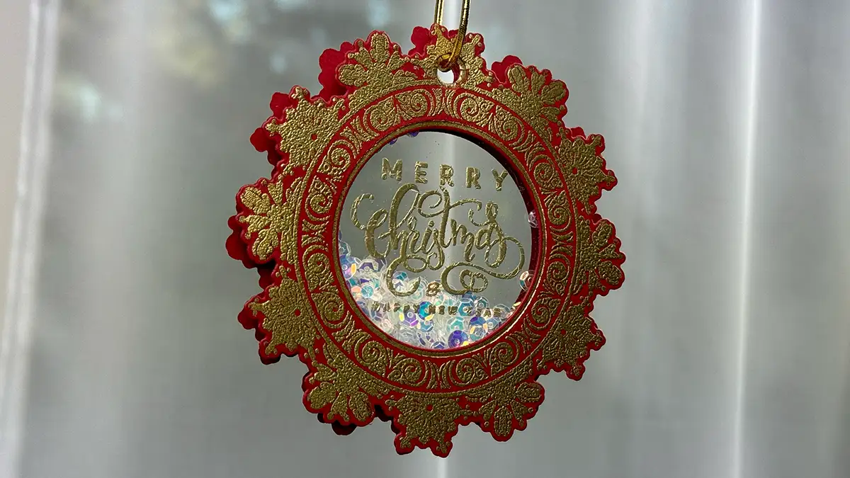 A red and gold christmas ornament hanging on a curtain, adding a festive touch to the Countdown to Christmas.