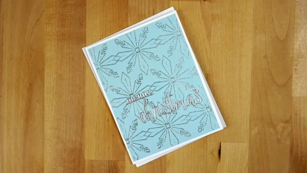 A blue card with a sparkly snowflake design on it.