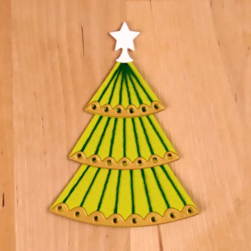 Stitchmas Day 1 - A green Christmas tree on a wooden surface.