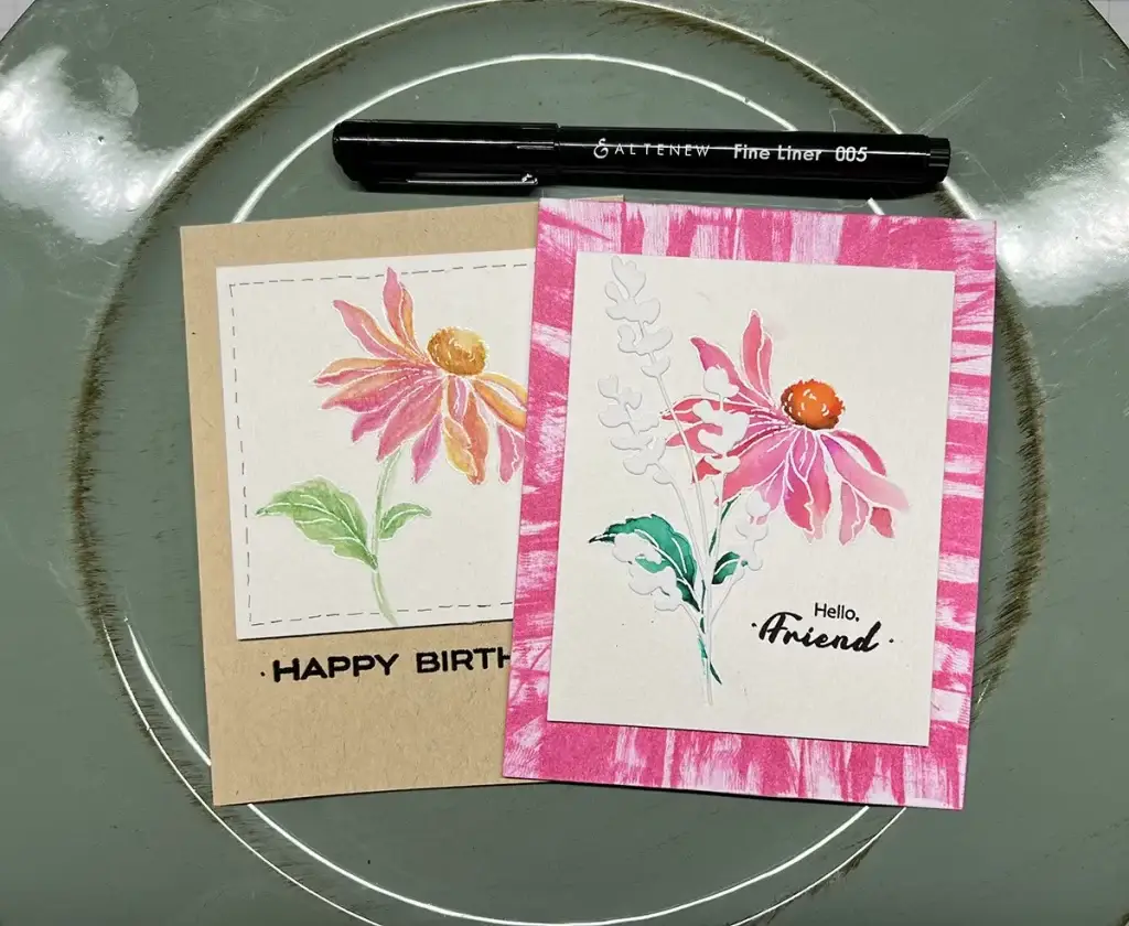 Two cards with pink flowers and a pen on a plate, showcasing 4 ways to watercolor.