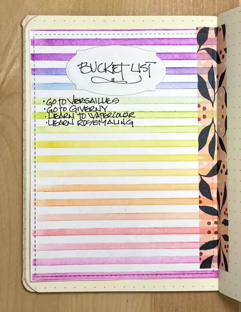 Crafters Traveler's Notebook with a rainbow striped cover and writing on it.