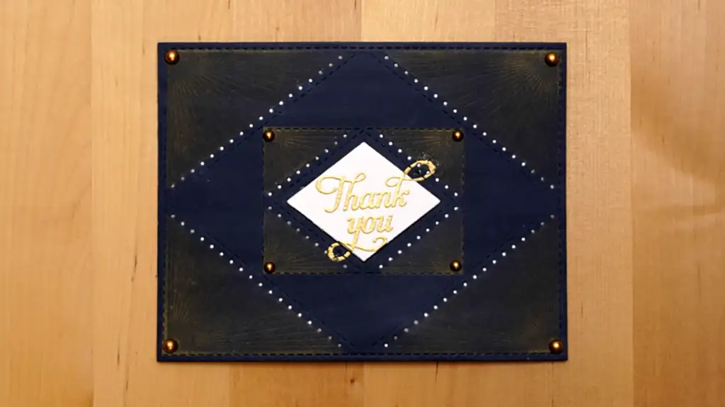 A thank you card adorned with stitching, resting on a wooden table.