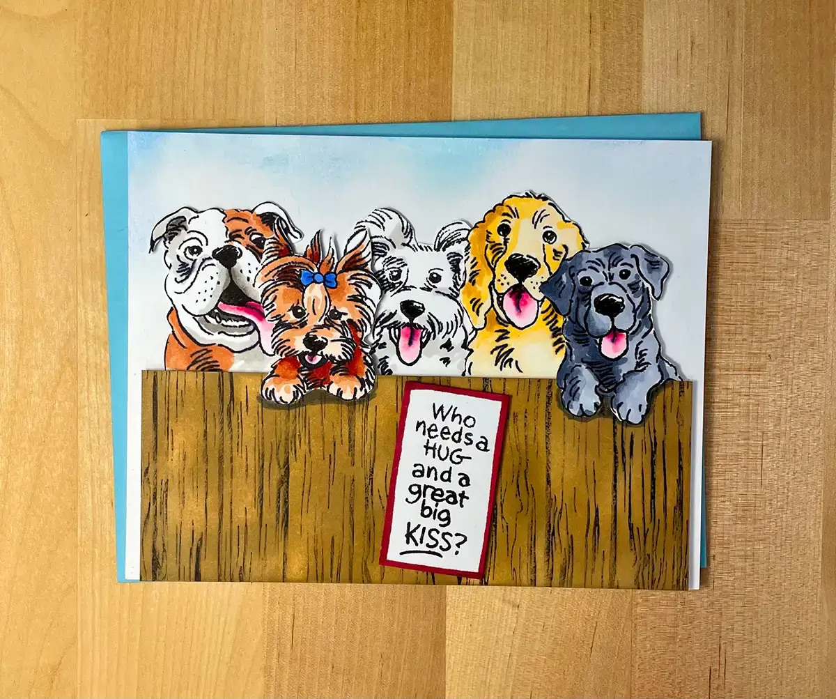 An adorable DIY greeting card featuring a group of dogs sitting on a fence.