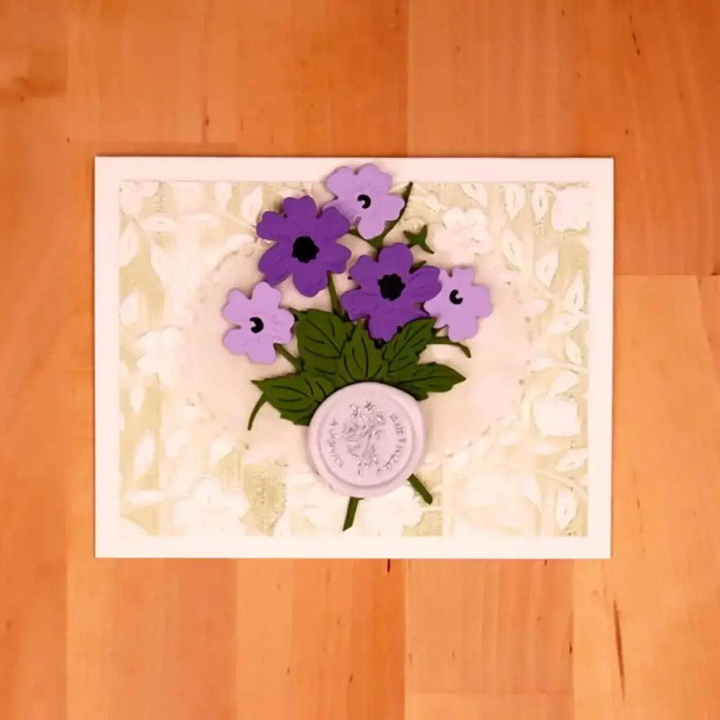 A floral greeting card with purple flowers on a wooden table.