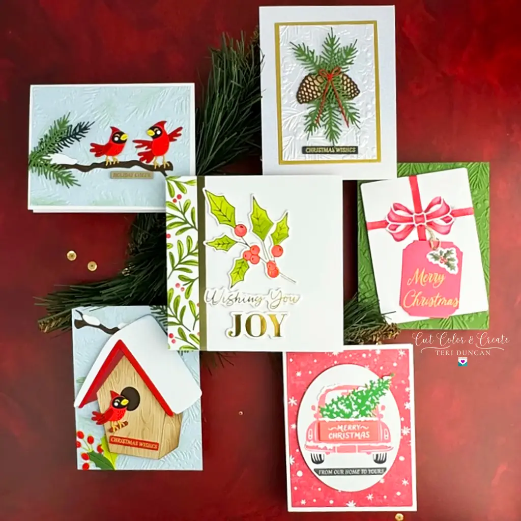 A display of six Christmas cards from Spellbinders with various festive designs, including birds, holly, a gift box, and a car with a tree. Some cards include text such as "Merry Christmas" and "Wishing you JOY." Perfect for July 2024 Monthly Clubs.