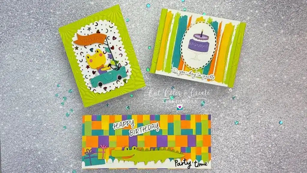 Three colorful handmade birthday cards with playful designs. One features a cat, another a cake, and the third an alligator. Each card has a unique layout on a glittery background.