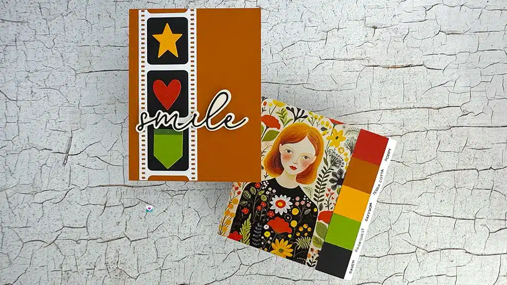 Two handmade cards on a cracked white surface: perfect for card making enthusiasts, one features a film strip, star, heart, and "smile" text; the other showcases an illustrated girl and offers fresh color inspiration.