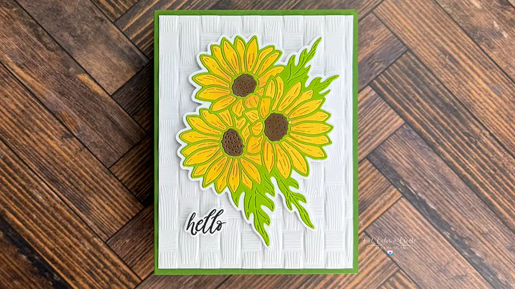 A greeting card with three yellow sunflowers and green leaves on a textured white background, featuring the word "hello" in black script—a charming idea for card making inspired by Yana’s Daisies collection.
