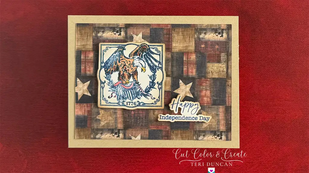 A handmade patriotic card featuring an illustrated eagle, the year 1776, stars, and text reading "Happy Independence Day" on a red and brown plaid background.