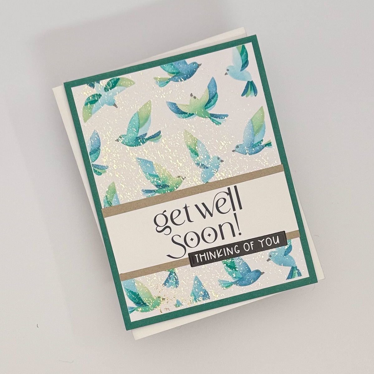 A "get well soon" Flit & Flitter greeting card, part of a set of 4 handmade cards, decorated with blue and green bird illustrations and the message "Thinking of you" on the front.