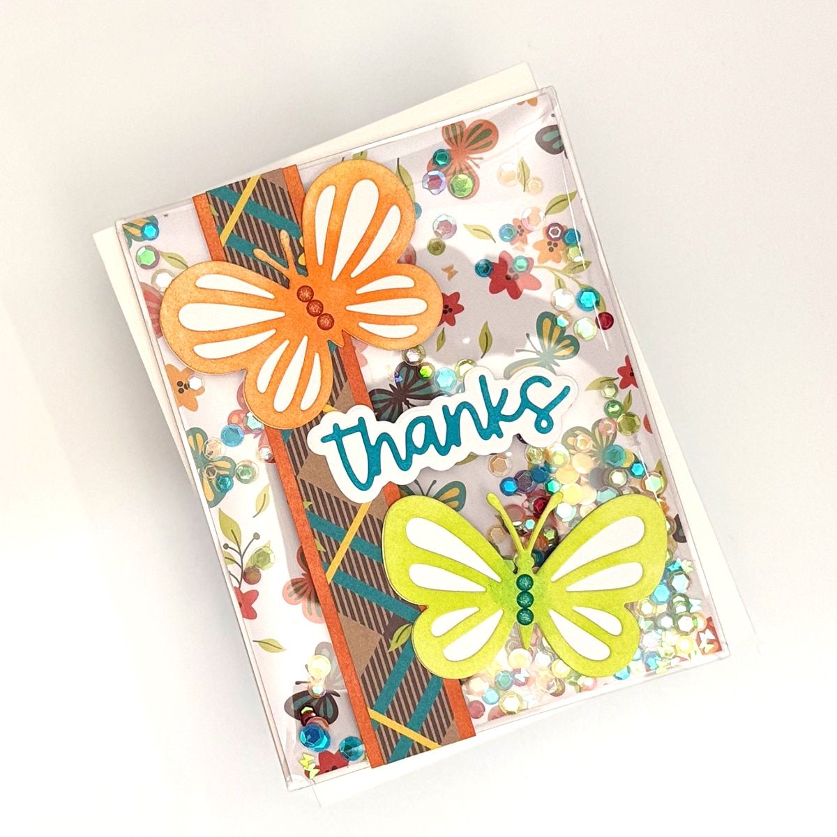Handmade Card featuring "thanks" text, two paper butterflies, colorful sequins, and a floral pattern on a crisp white background.