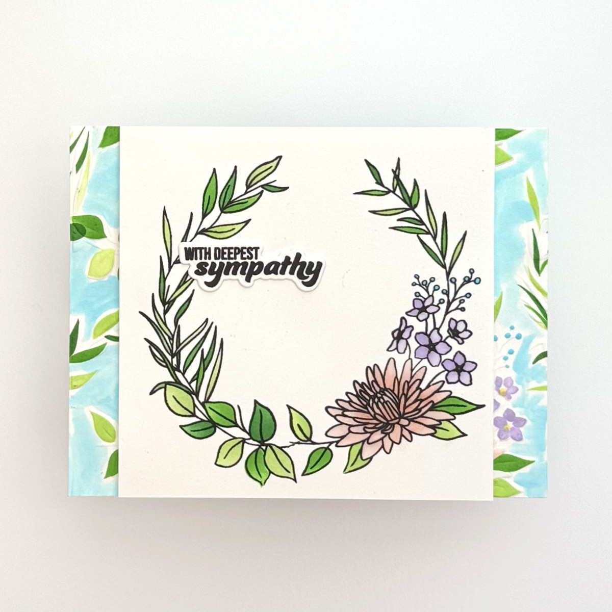 A Floral Sympathy card featuring a floral wreath and the text "With deepest sympathy" on a white background with green and blue accents.