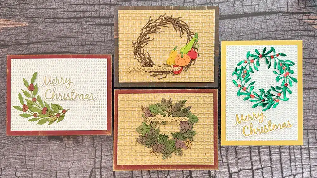 Four handmade greeting cards with wreath designs and holiday greetings, arranged on a wooden surface. Two cards say "Merry Christmas," and two feature autumn-themed wreaths. Cards created using Spellbinders Texture & Foliage Collection