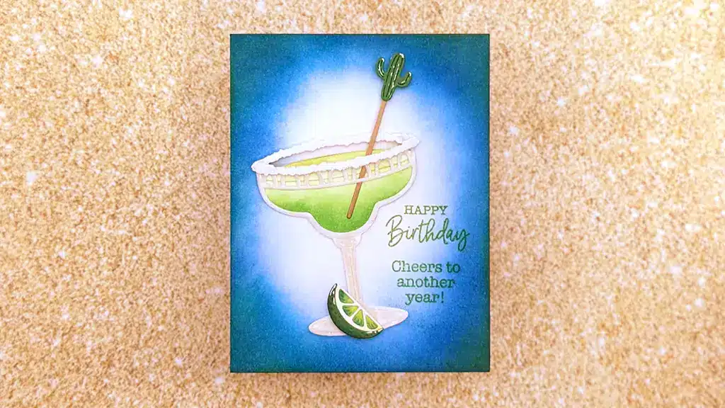 Greeting card from Happier Hour Cards features a margarita glass, lime slices, and a cactus-shaped stirrer. Text reads “Happy Birthday. Cheers to another year!” Perfect inspiration for DIY cards or learning how to make festive greetings.