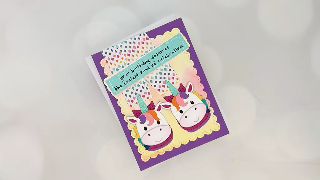 A colorful handmade birthday card featuring die-cuts of two unicorn faces, rainbow decorations, and the text "your birthday deserves the craziest kind of celebration." Perfect for cozy cards and creative card making.