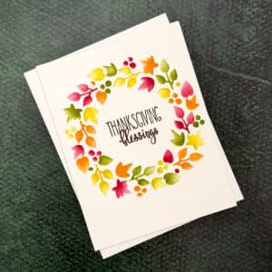 A Thanksgiving Card featuring a vibrant Blessings Wreath and the words "Thanksgiving blessings" on the cover, set against a green textured background.