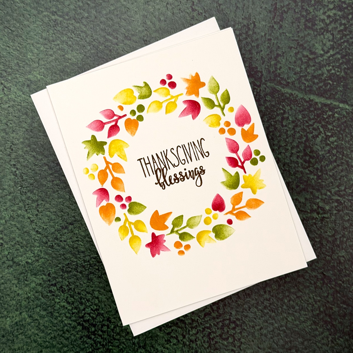 A Thanksgiving Card featuring a vibrant Blessings Wreath and the words "Thanksgiving blessings" on the cover, set against a green textured background.